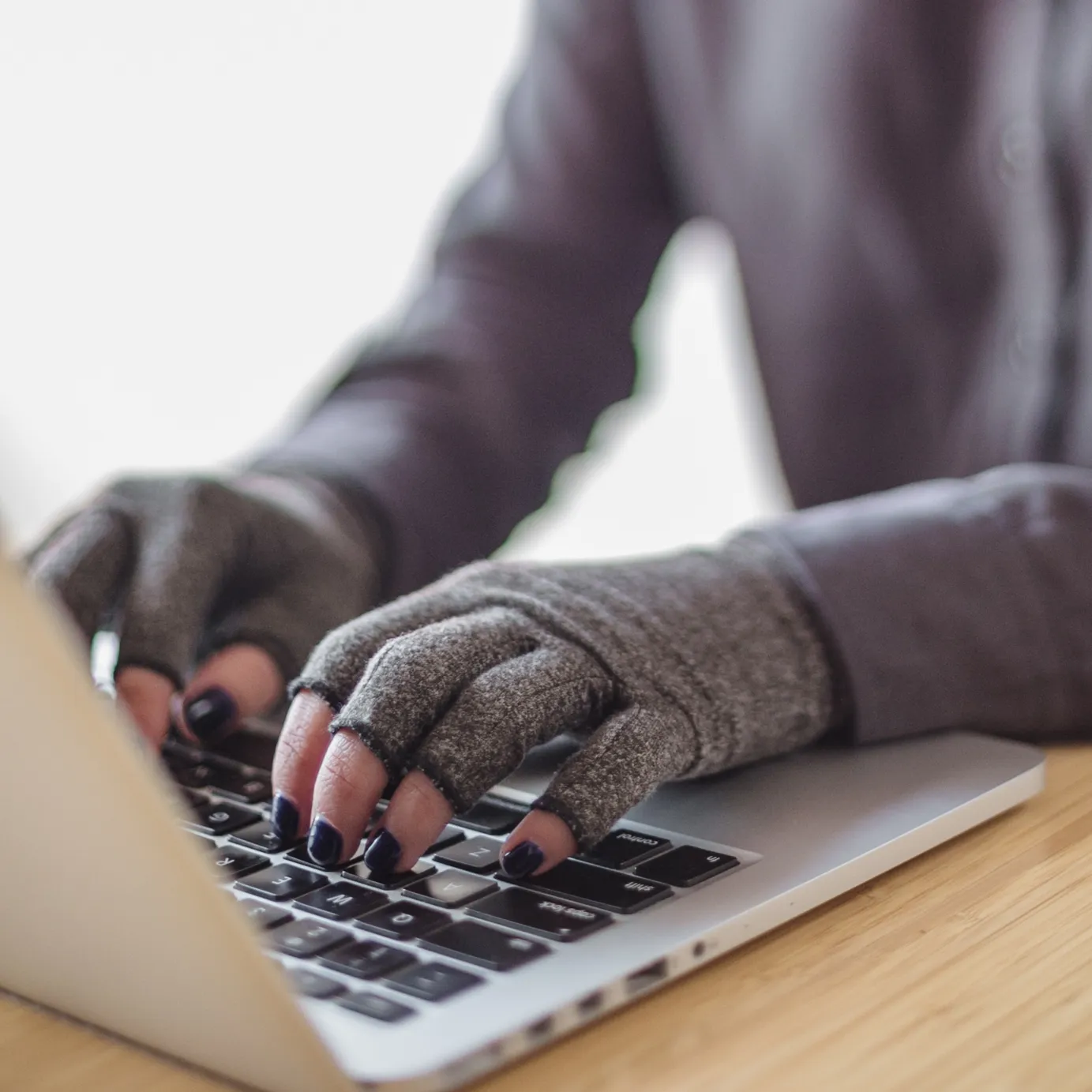 Closeup of hands in compression gloves, typing on a computer