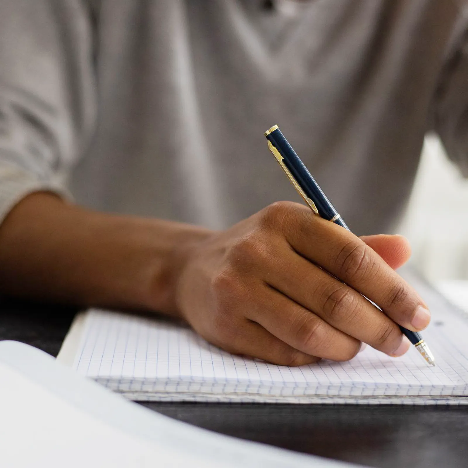 Closeup of a Black person writing in a notebook