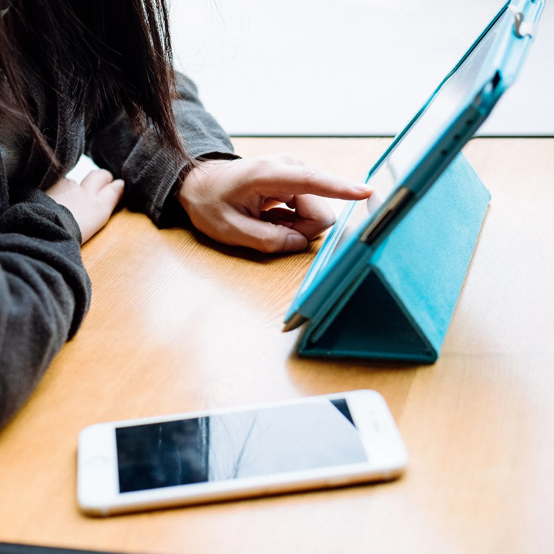 Closeup of a person using a tablet in a turquoise case