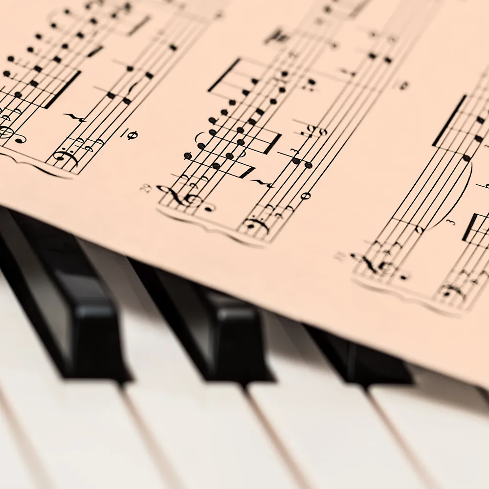 A piece of sheet music lies diagonally across piano keys